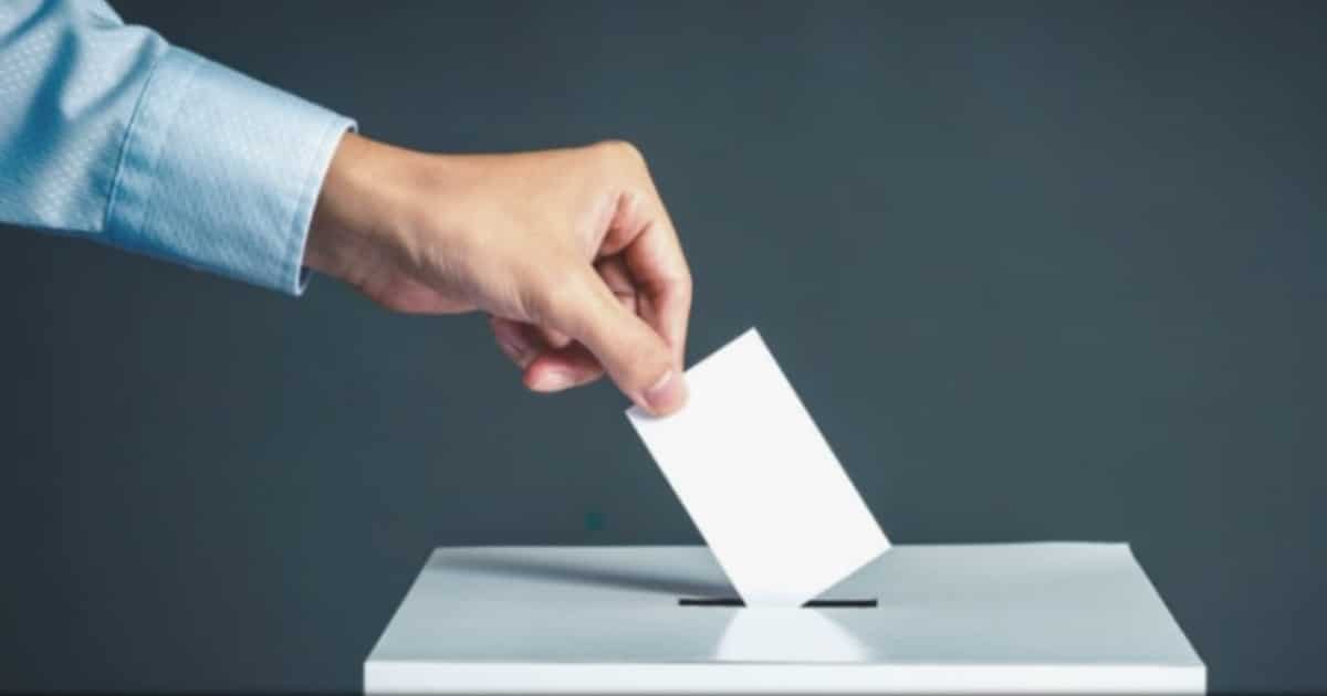 Voto sendo depositado em urna eleitoral.