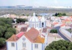 Vista aérea de vila portuguesa com igreja e rio.
